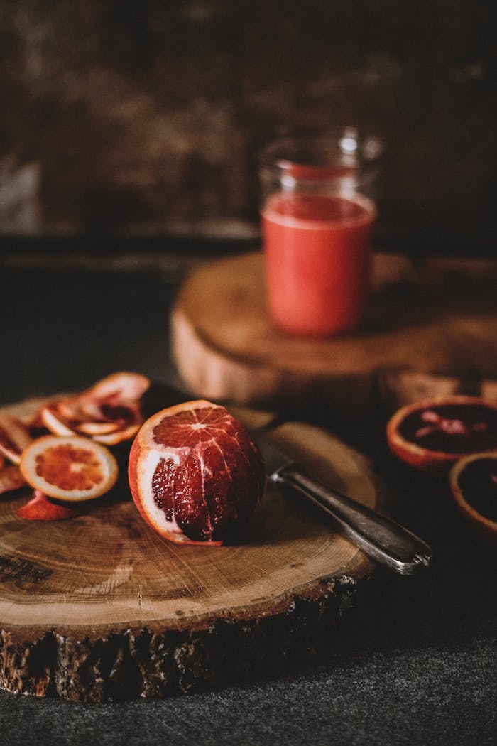 Blood orange juice and sliced citrus on a rustic wooden board, highlighting freshness and natural appeal.